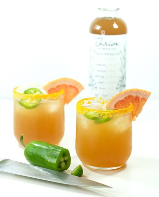 spiced paloma cocktail next to a bottle of thrive recovery