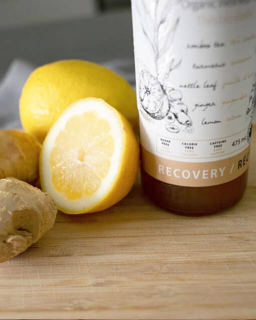 bottle of thrive remedies sitting on a cutting board with lemons and ginger