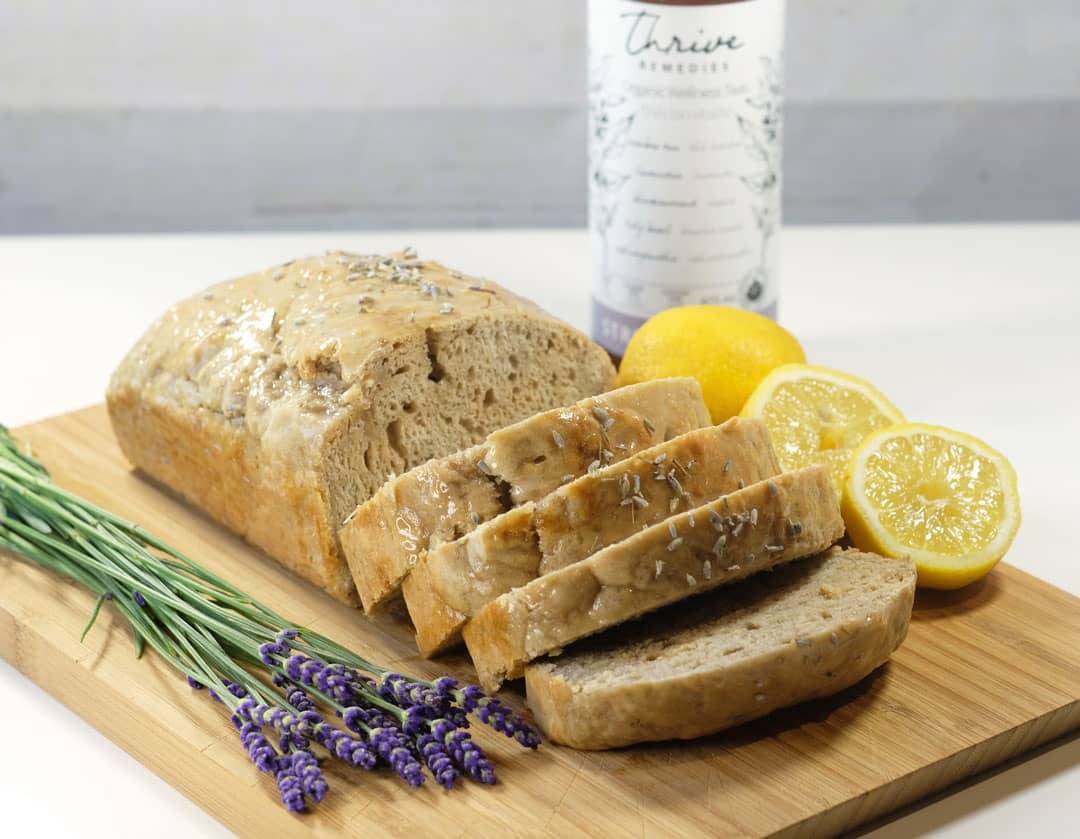 lemon lavender loaf on a cutting board next to some fresh lavender flowers and lemons