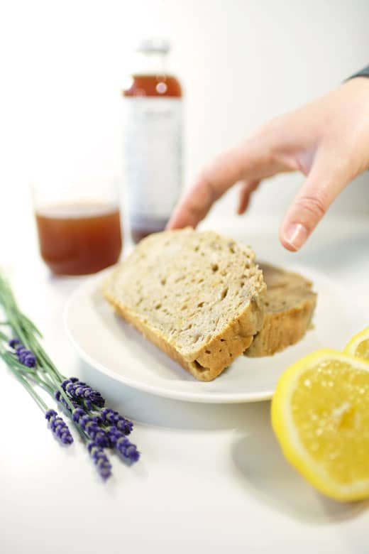a persons hand grabbing a slice of vegan lemon lavender loaf
