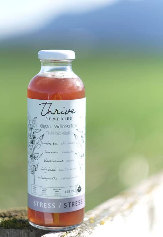 bottle of thrive sitting on a fence in in front of a field
