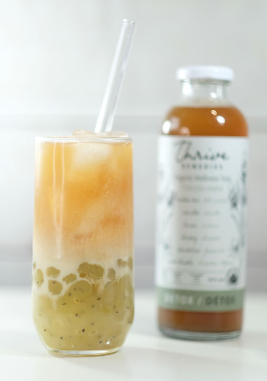 detox-bubble-tea-with-kiwi-tapioca-pearls bubble tea next to a bottle of thrive detox
