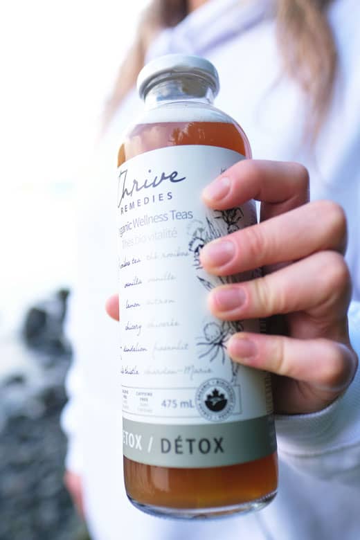 woman's hand holding a bottle of thrive remedies detox blend tea