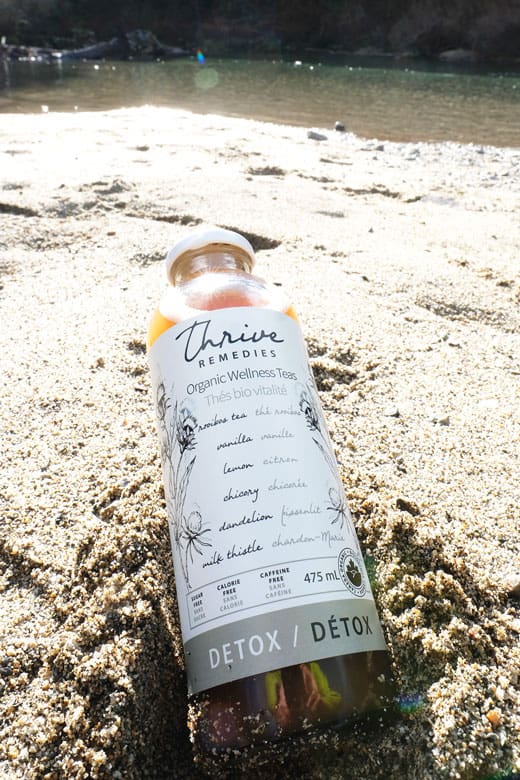 bottle of detox in the sand at a lake